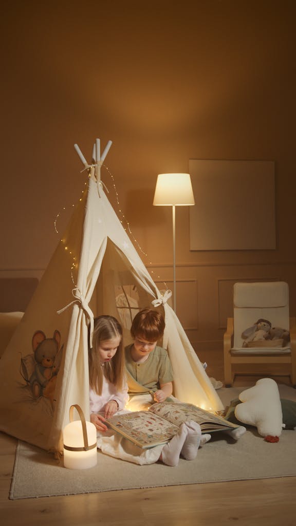 A charming scene of two children bonding while reading in a cozy indoor tent.