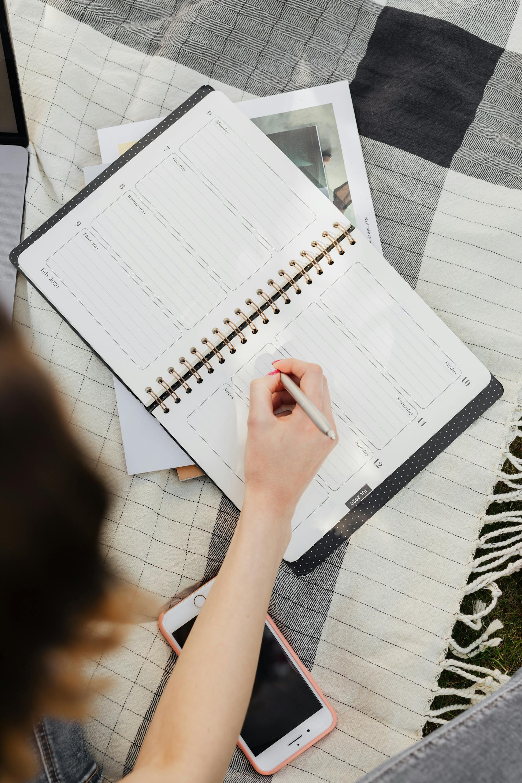 Young woman writing in her planner while enjoying a sunny day outdoors.